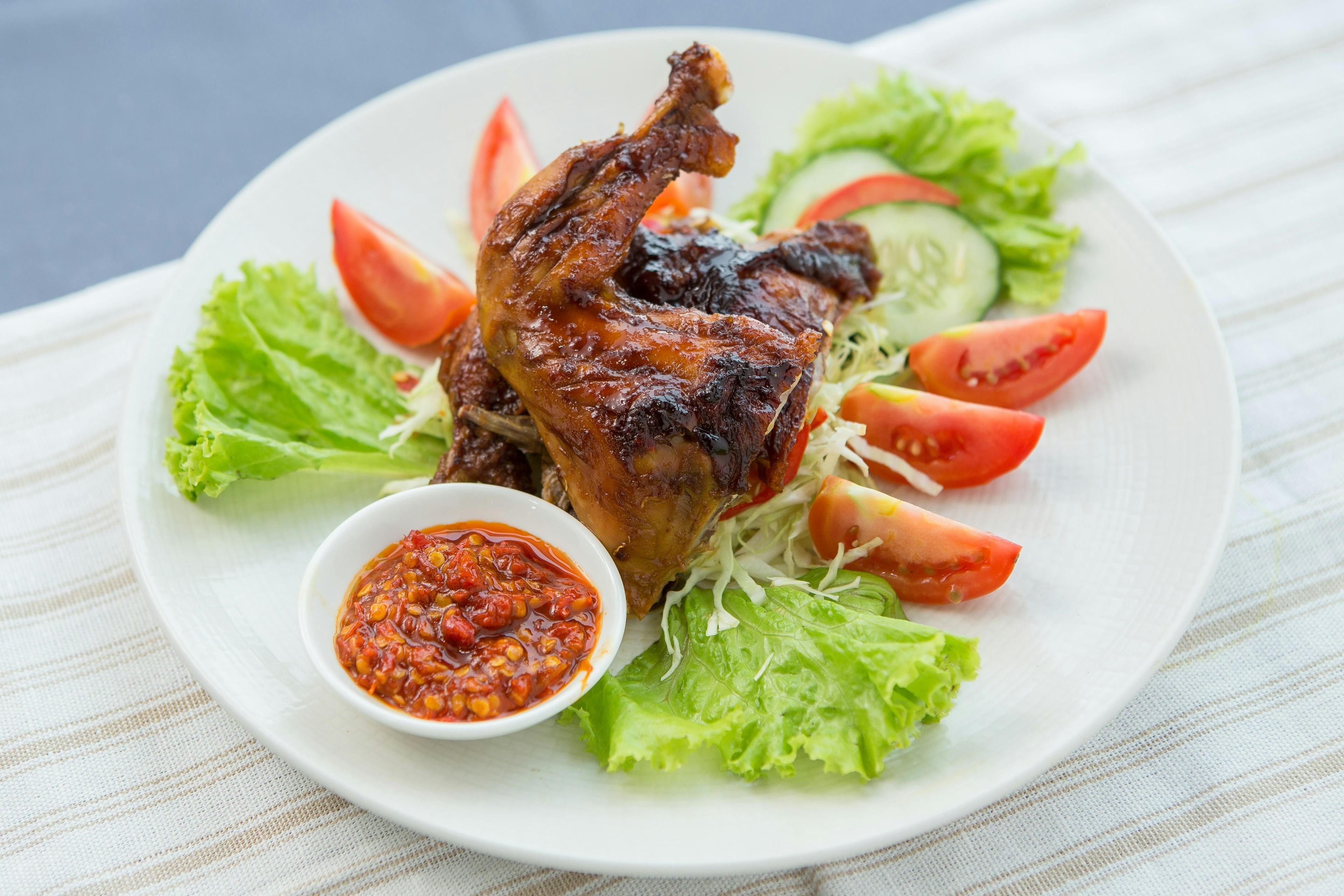 Ayam bakar di piring dengan sambal dan lalapan